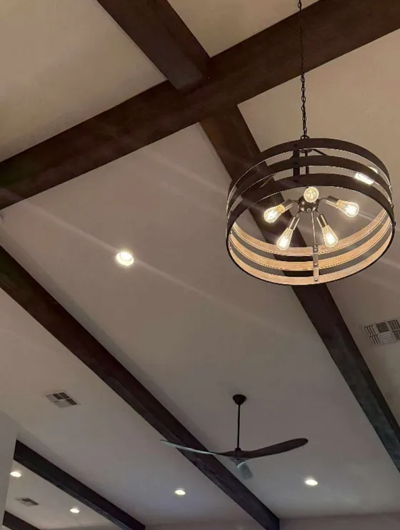 Dark wood ceiling beams converging at a drum chandelier