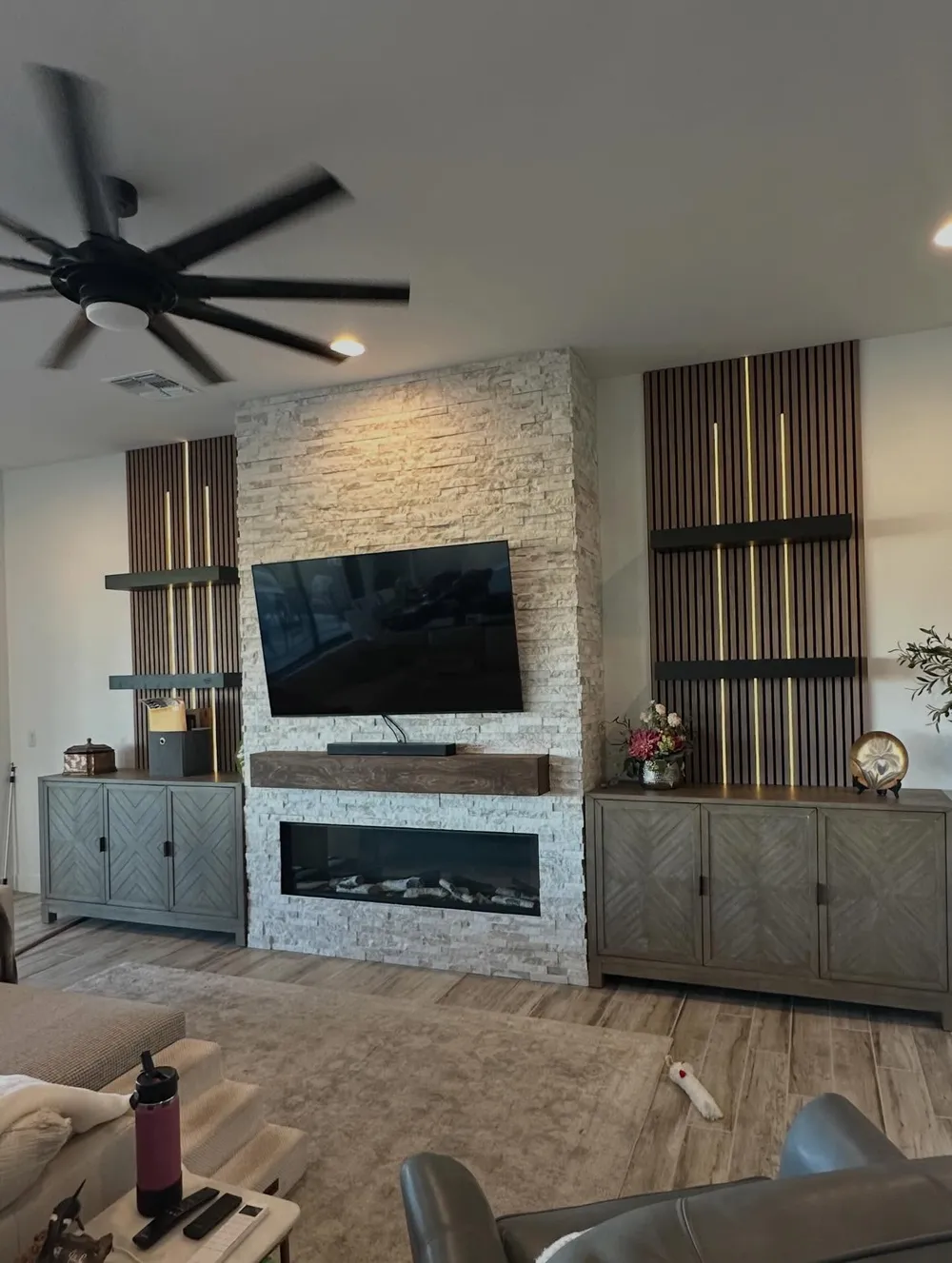 Stone fireplace wall with brass lit slat shelving.