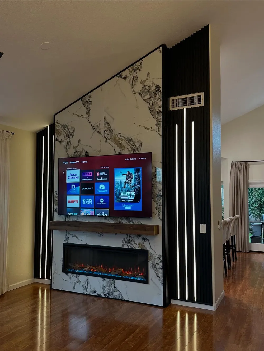 Marble slab media wall flanked by black fluted wood panels with integrated LED lighting