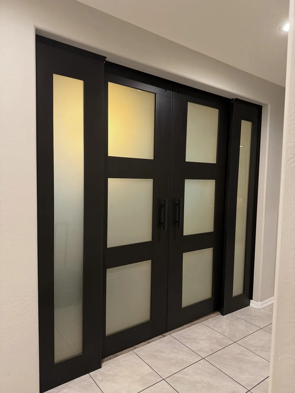 Paired black frame barn doors with frosted glass panes