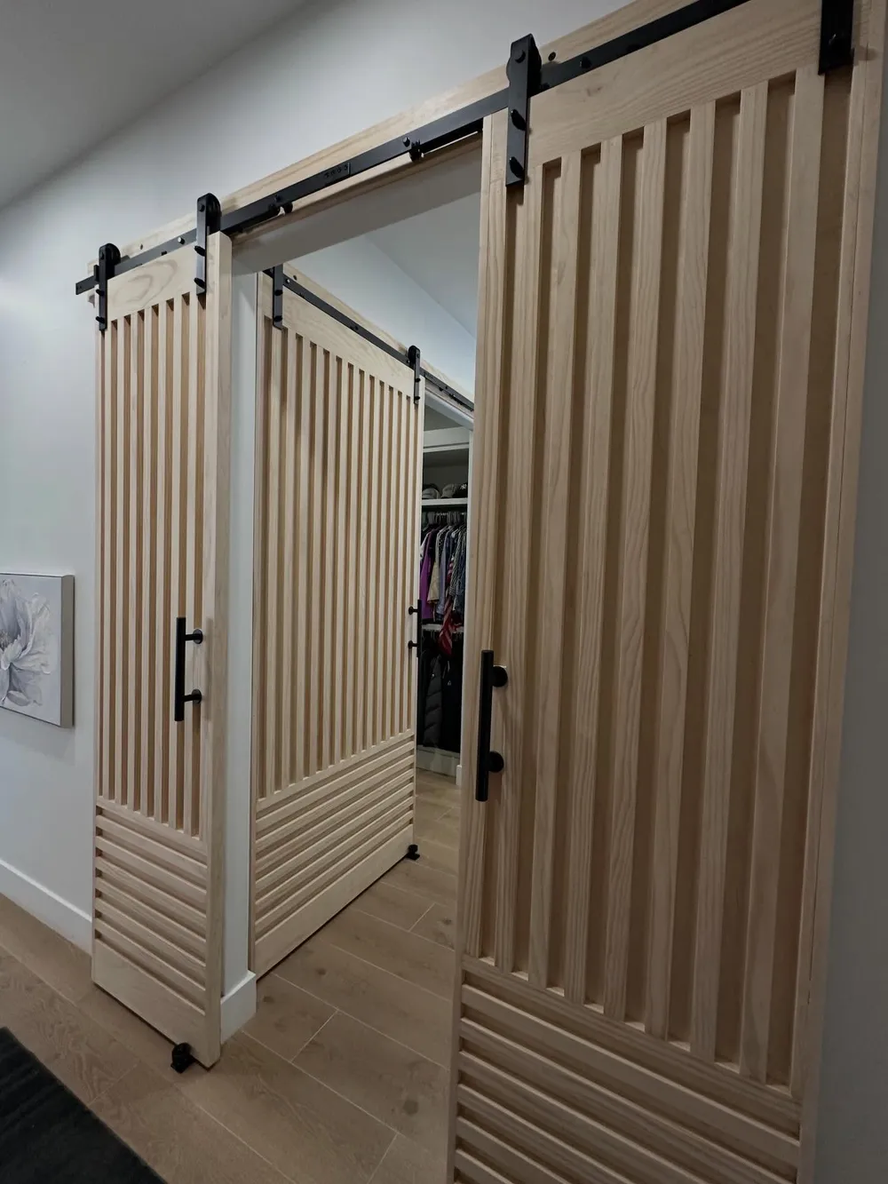 Raw wood slat sliding doors opening into a walk in closet