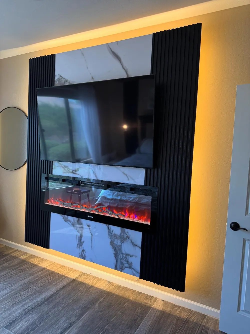 Marble and fluted black panel fireplace wall with warm backlighting