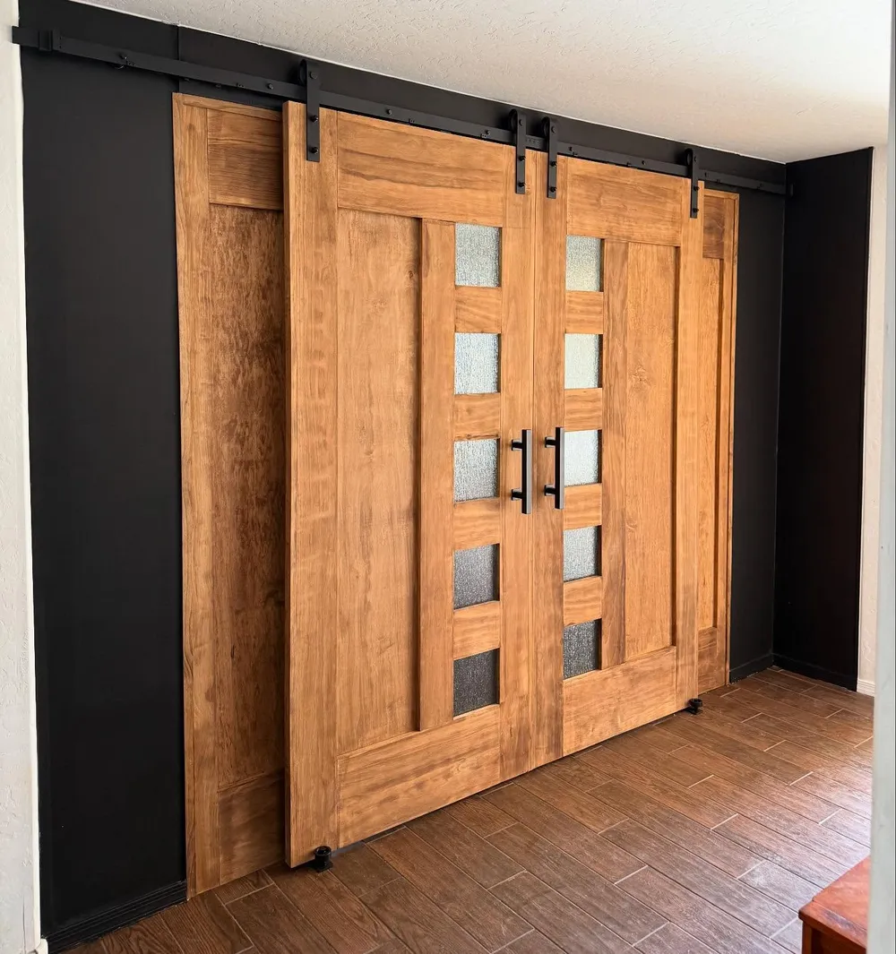 Warm wood double barn doors with frosted glass on blackened rail hardware