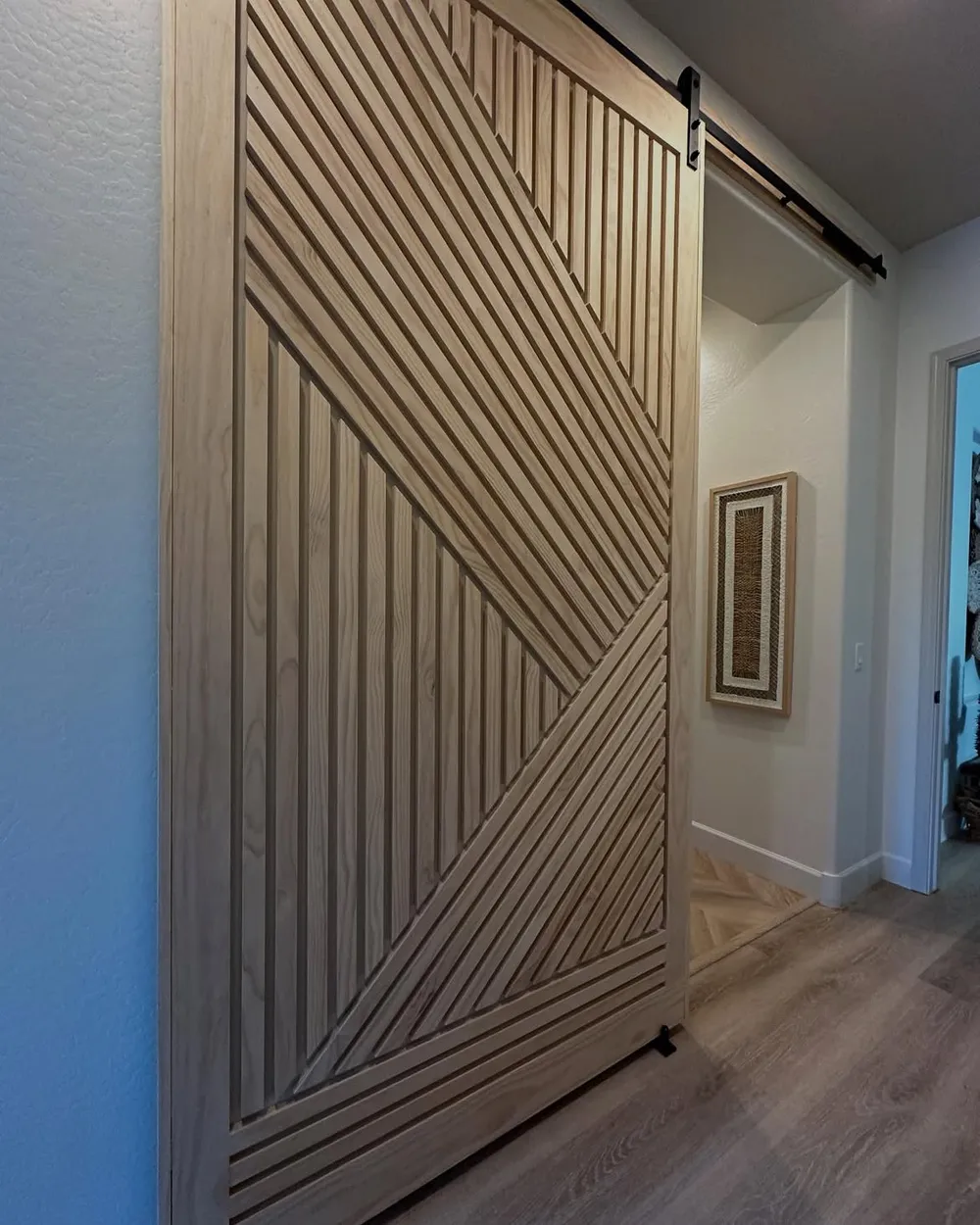 Geometric slat barn door in raw ash on a black rail