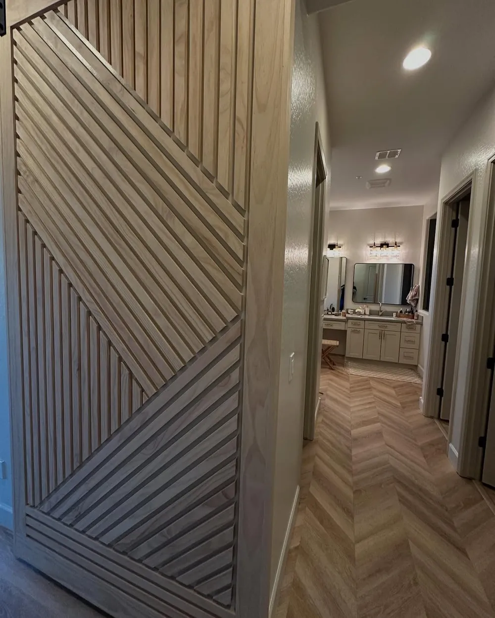 Sliding barn door opening onto a bathroom with herringbone oak floor