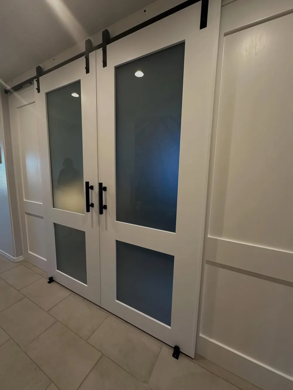 Frosted glass barn doors on a matte black rail