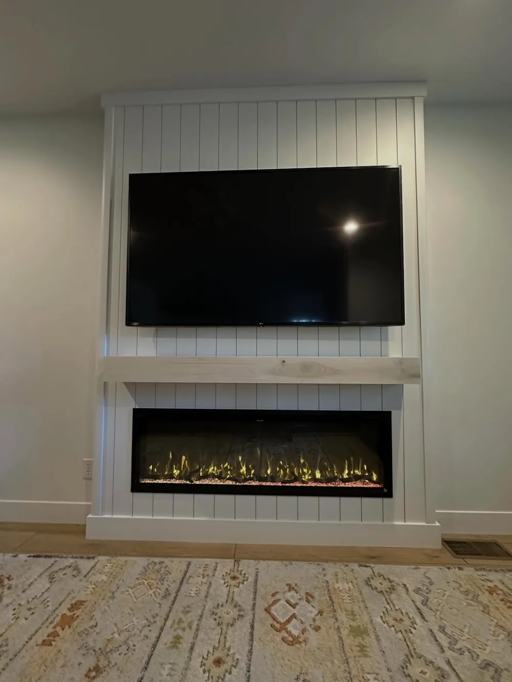 The shiplap fireplace wall from the sitting area, warm mantel wood against crisp white.