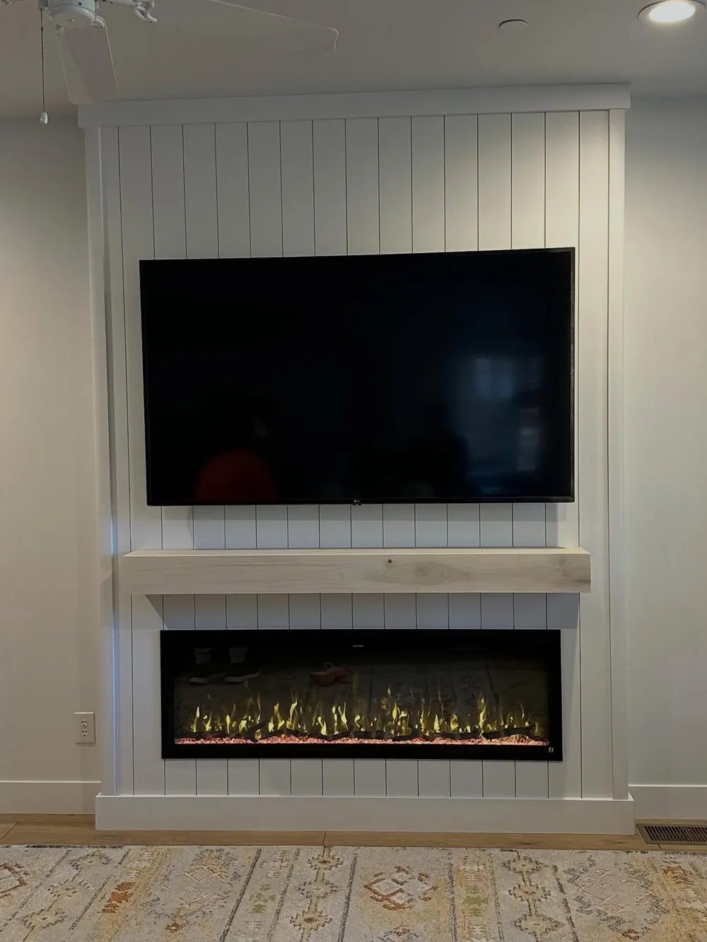 Shiplap fireplace wall with floating mantel, set in a bright room with a ceiling fan.